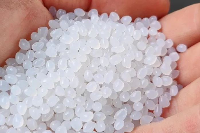 weißes Kunststoffrecyclat auf einer Hand